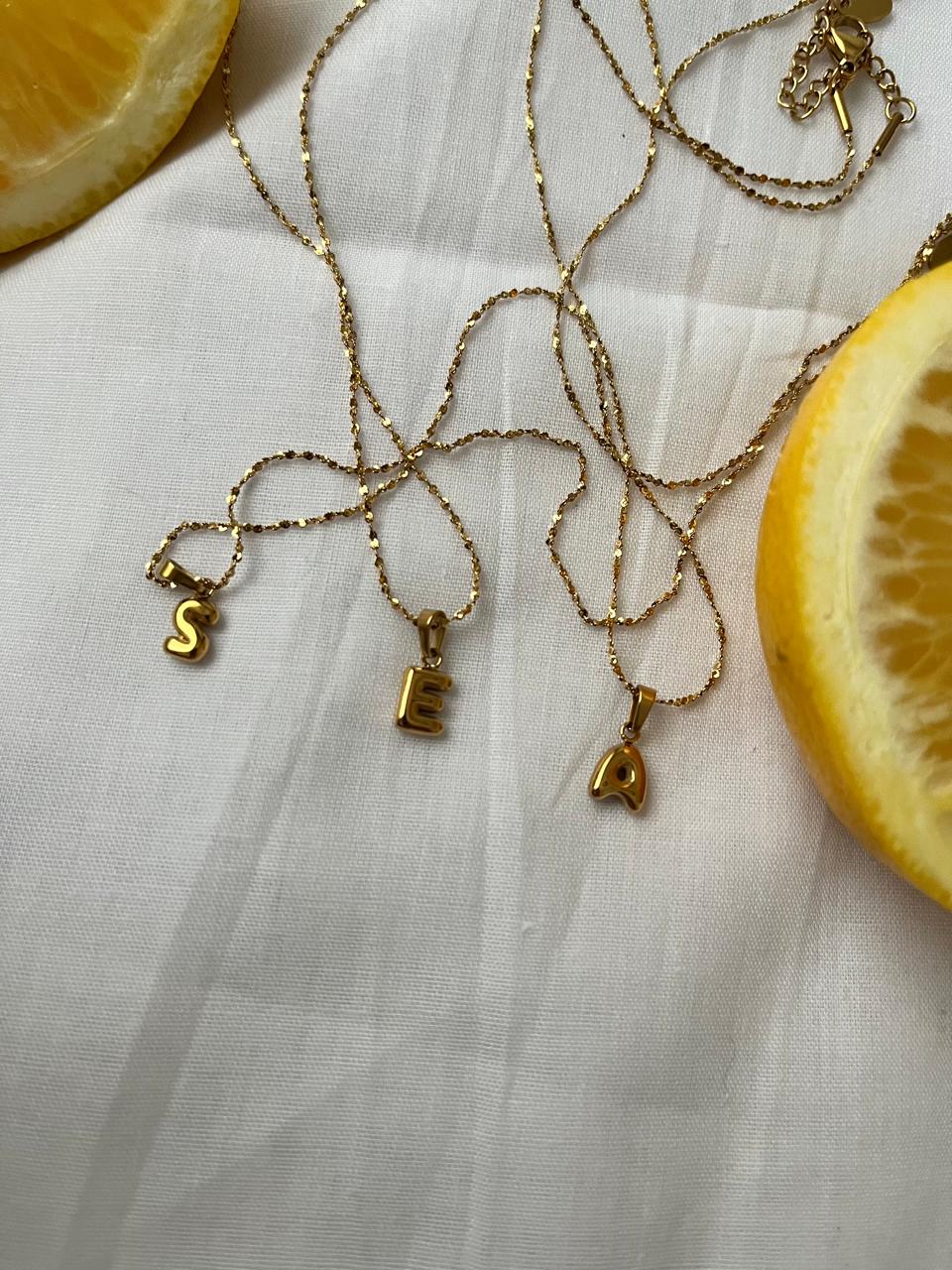 Layered bubble-style gold letter pendants on gold chains