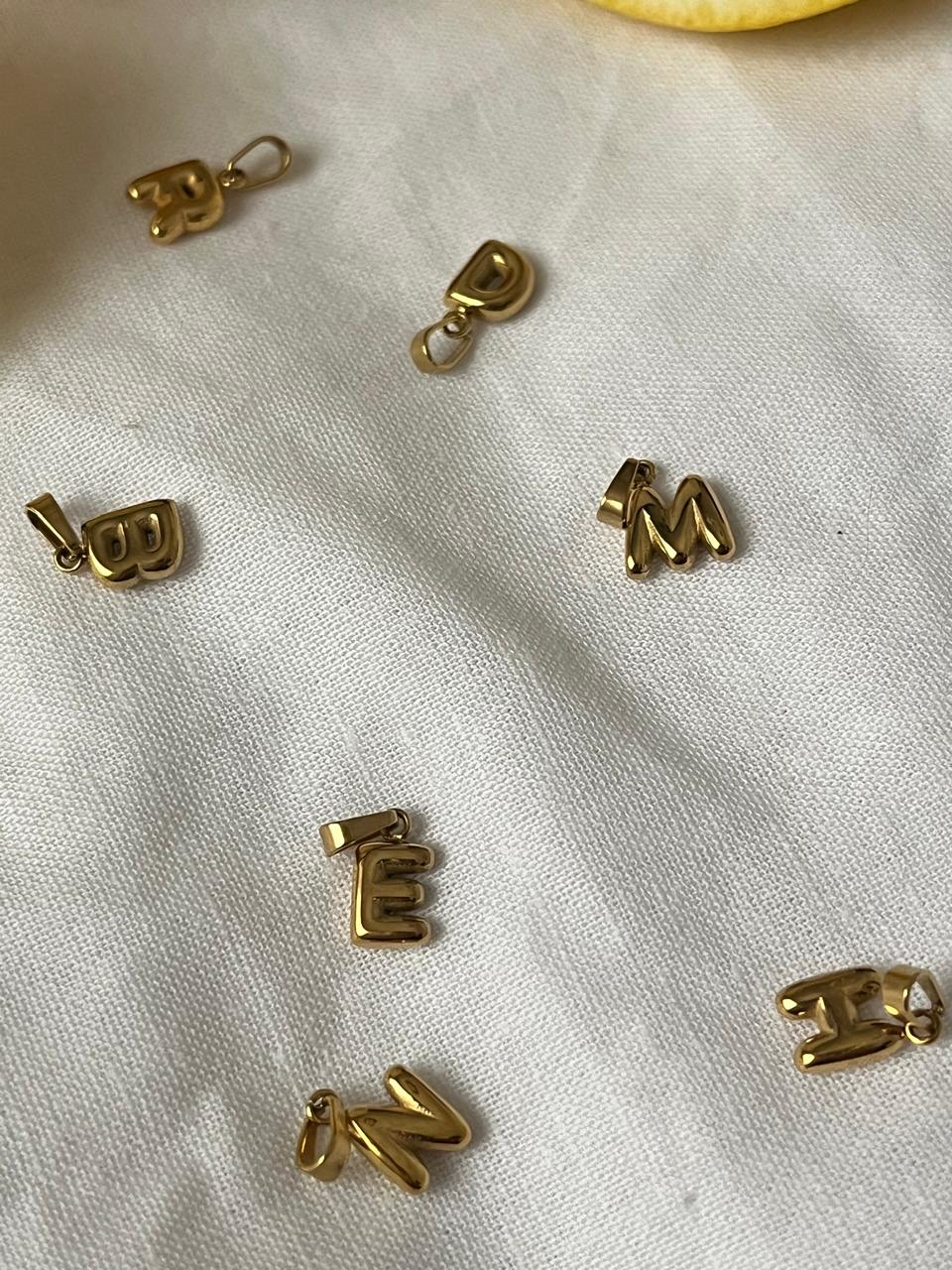 Close-up of bubble-style gold letter pendant on gold chain