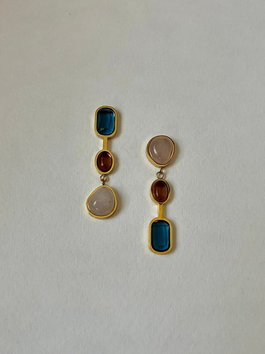 Pair of earrings with multicolored stones on a light gray background